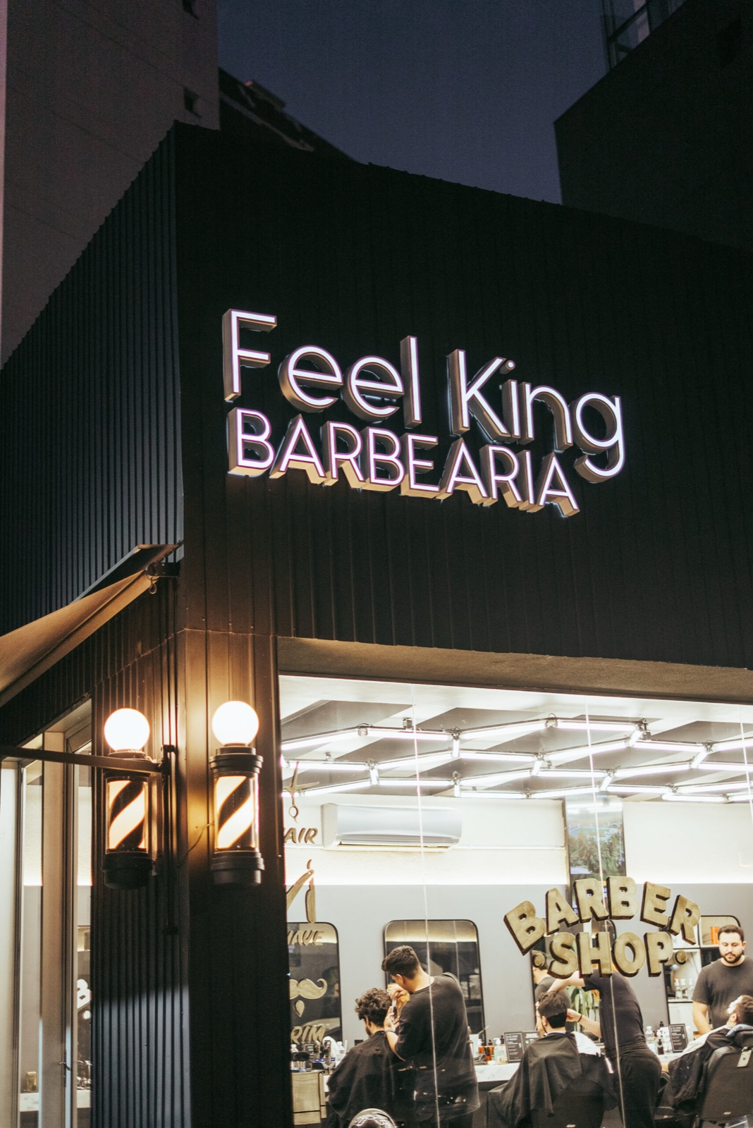 Fachada iluminada da Feel King Barbearia à noite